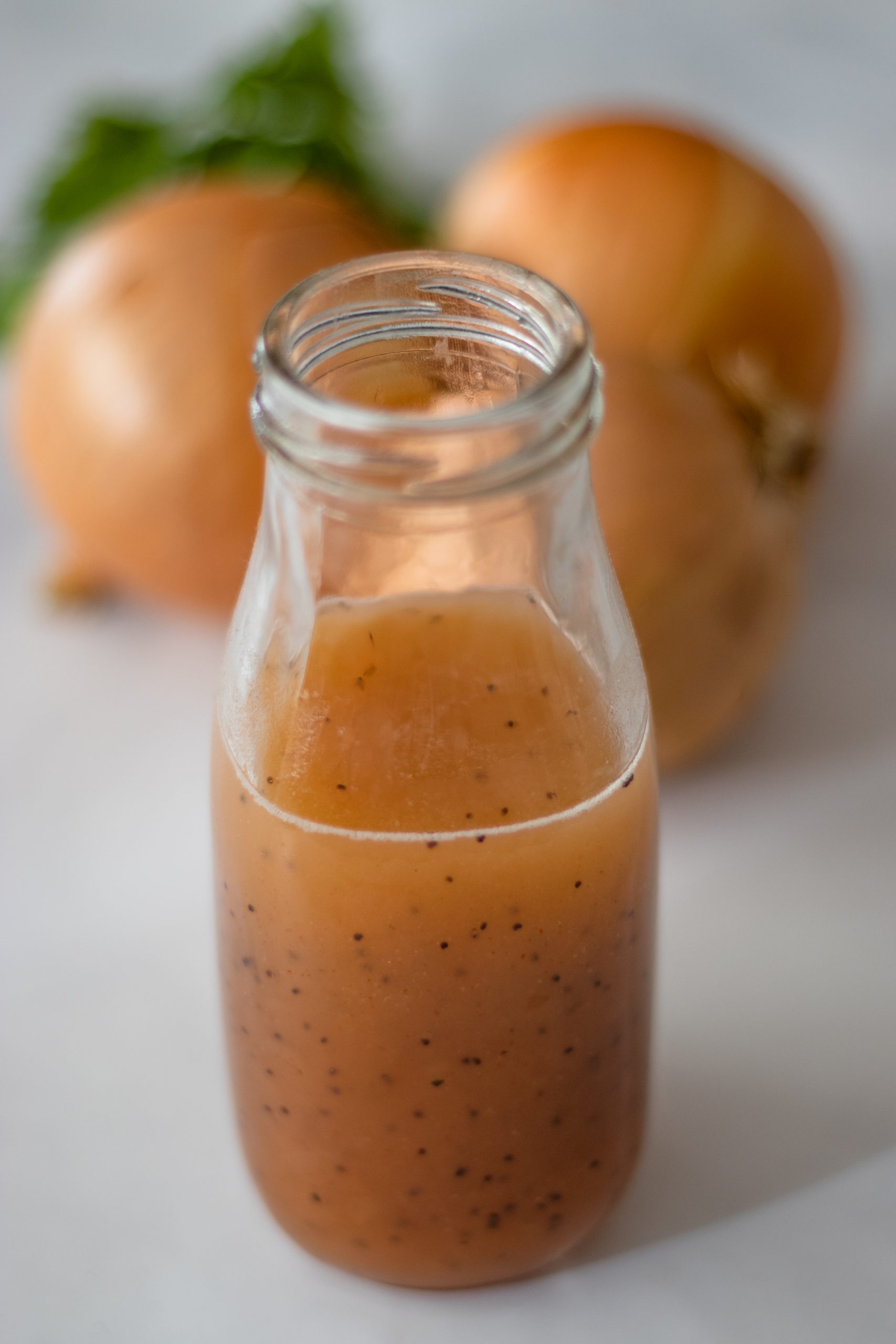 A jar of sweet onion sauce with 3 onions and parsley in the background