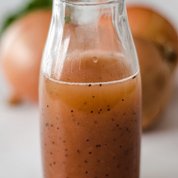 A jar of sweet onion sauce with 3 onions and parsley in the background