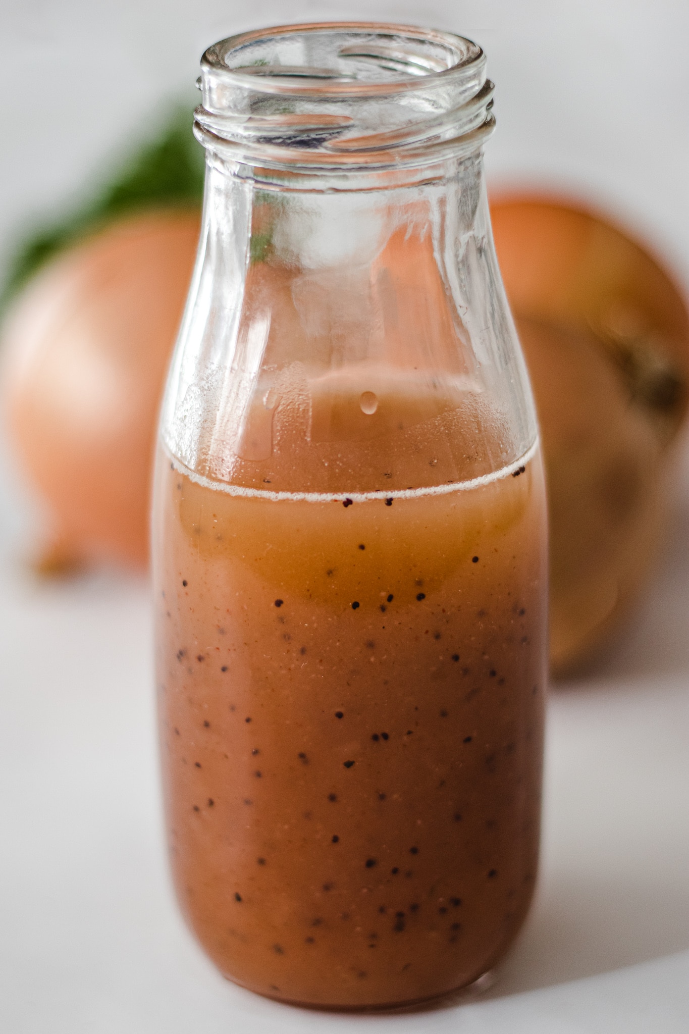 A jar of sweet onion sauce with 3 onions and parsley in the background