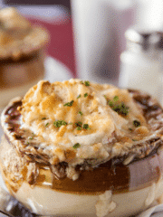 A close up shot of french onion soup with melty cheese on top