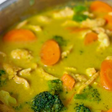 A stainless steel pan loaded with yellow Thai curry with broccoli, carrots and chicken