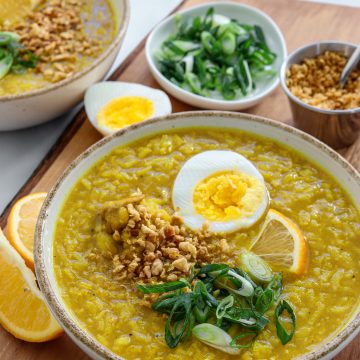 2 bowls loaded with a rich Arroz Caldo recipe - topped with a hard boiled egg, green onion, crispy fried garlic and a lemon wedge.