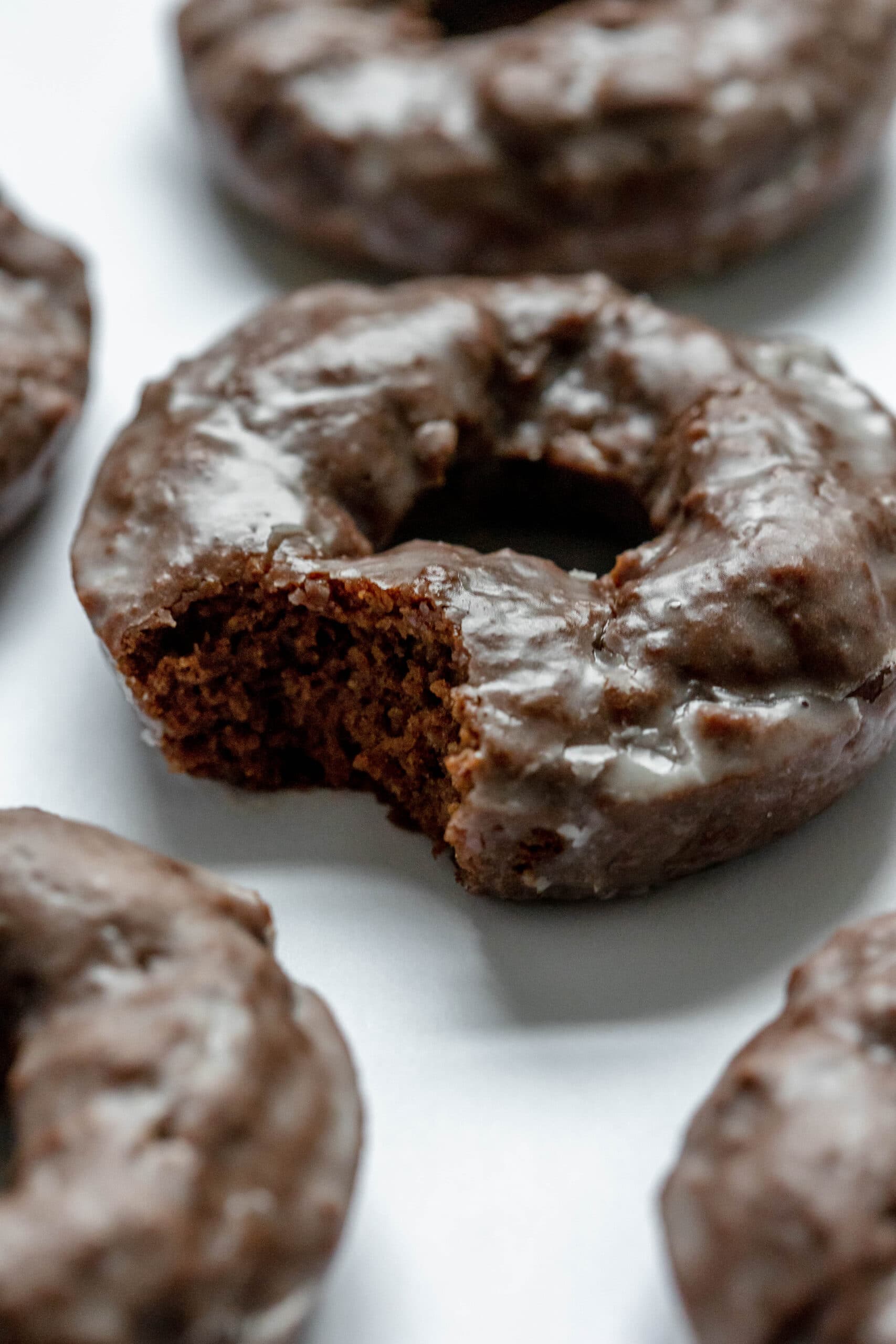 A close up picture of a donut with a bite taken out of it and other donuts around it.