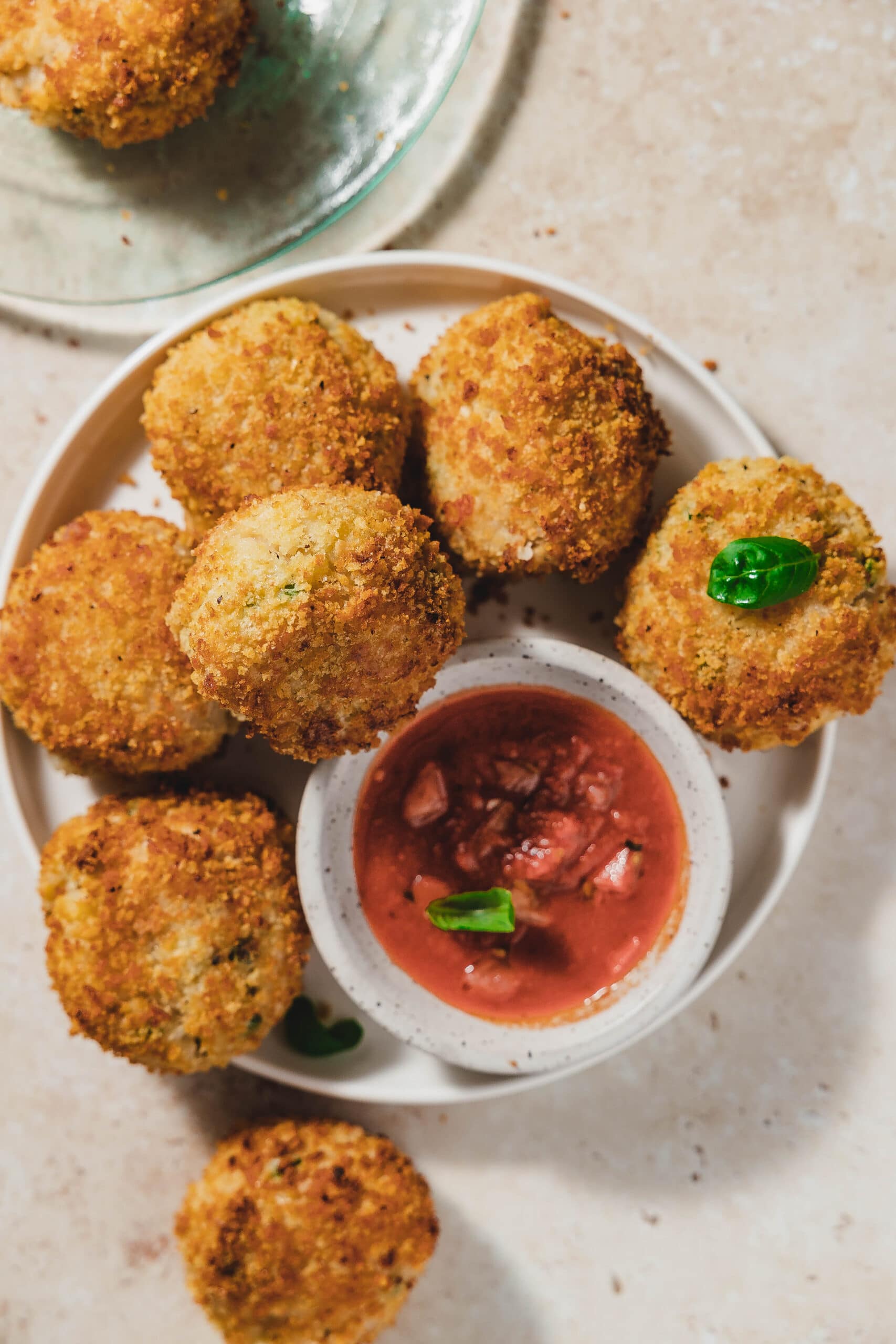 A shot of the arancini with marinara and basil on a plate ready to eat.